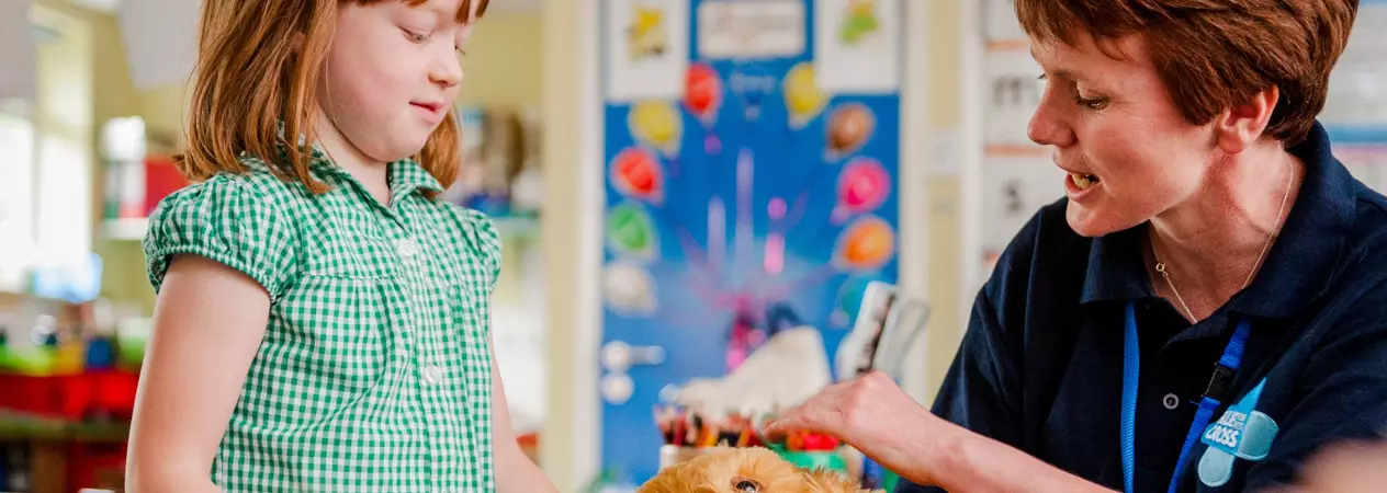 A volunteer education speaker shows a child how to pet a dog.