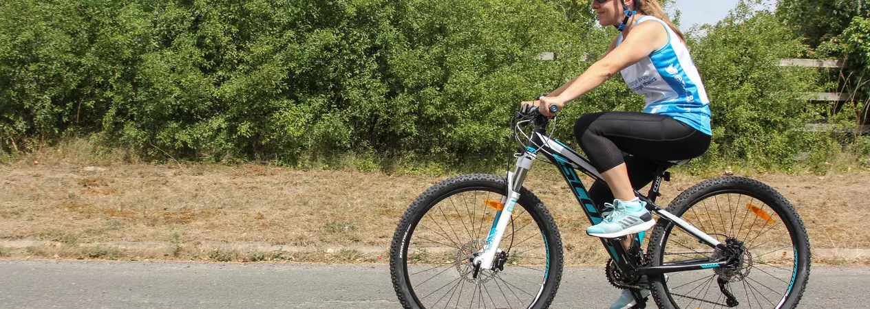 A lady cycling her bike down an empty road as part of a charity challenge event 