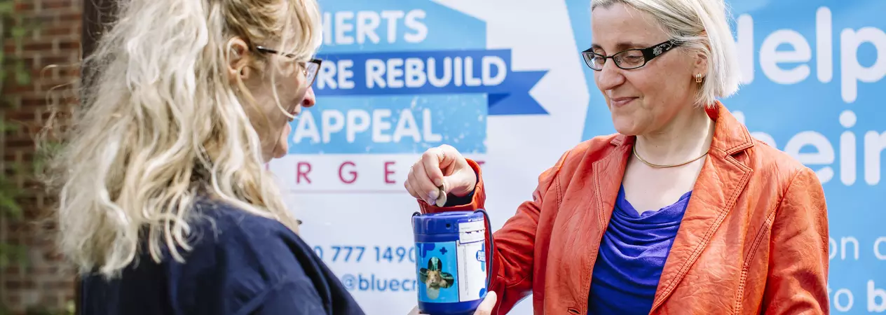 A Blue Cross volunteer receives a donation from a member of the public.