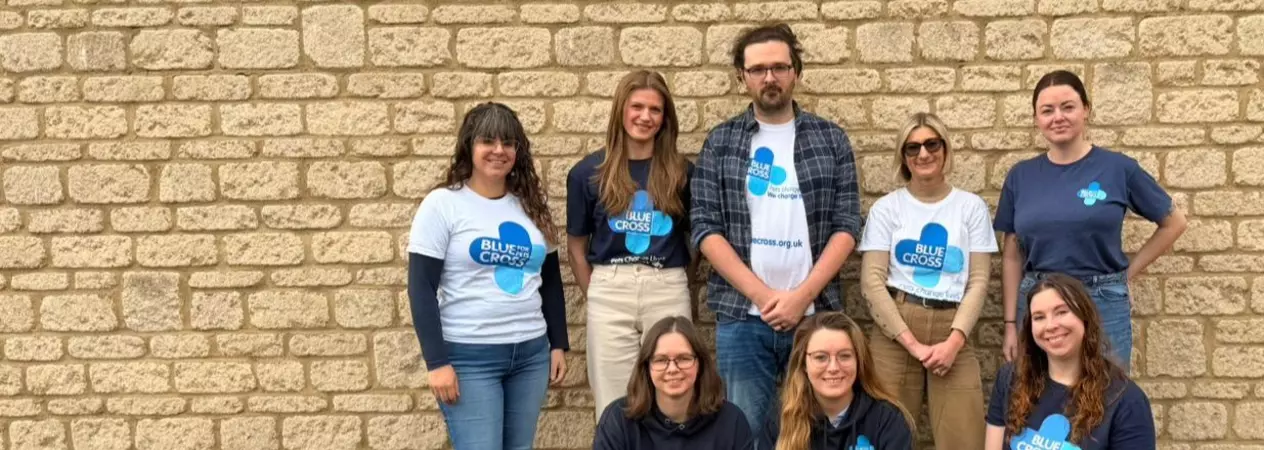 A group photo of the fundraising team at Blue Cross. They are all wearing Blue Cross clothing and smiling at the camera.