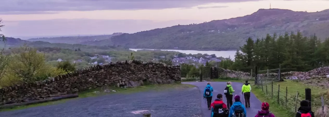 A group of adults trekking back down Snowdonia after taking part in the challenge event Snowdon by Night