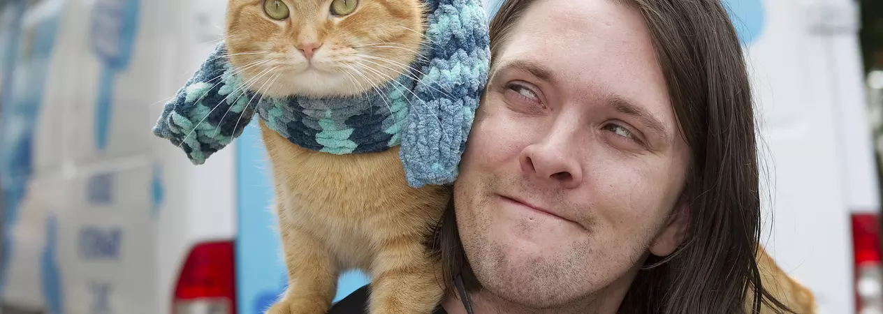Street cat Bob sits on James Bowen's shoulder by the Blue Cross mobile clinic which helped them through tough times