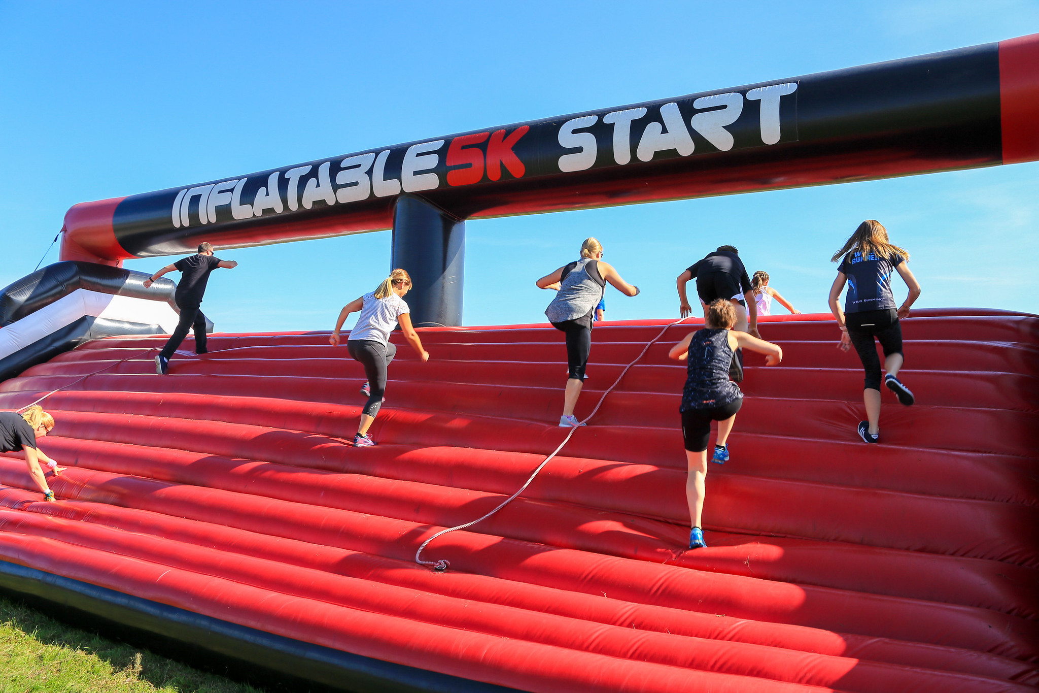Inflatable 5k participants climb over an inflatable obstacle.